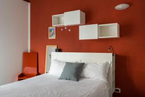 a bedroom with a white bed with an orange wall at Boldrini apartment with balcony by Wonderful Italy in Bologna