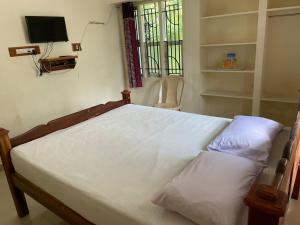 a bedroom with a bed and a tv on the wall at Sarah Residency in Thanjāvūr