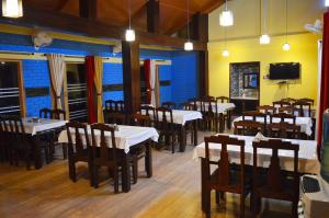 a dining room with tables and chairs and a tv at Hotel Burans & Restaurant in Chakrāta +21 photos
