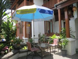 una mesa y sillas con una sombrilla en el patio en Baanlek Home Stay en Chiang Mai