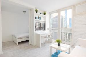Biały salon z biurkiem i łóżkiem w obiekcie Rondo ONZ Business Apartment w Warszawie