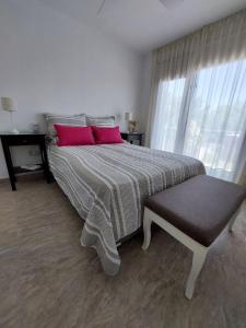 1 dormitorio con 1 cama grande y 2 almohadas rosas en Bahía Pellegrini en Tandil