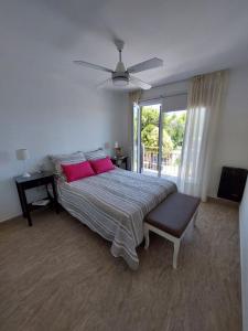 1 dormitorio con 1 cama con almohadas rosas y ventilador de techo en Bahía Pellegrini en Tandil