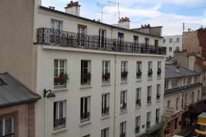 - un bâtiment blanc avec un balcon sur le côté dans l'établissement Hotel Telemaque, à Paris