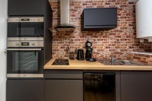 una cucina con elettrodomestici neri e un muro di mattoni di Location d'appartements - Cosysejour - Calme Fibre Netflix ad Amiens