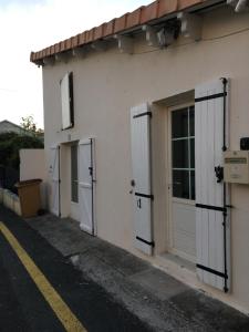 ein weißes Gebäude mit Seitentüren in der Unterkunft Le Welcome in Coutras