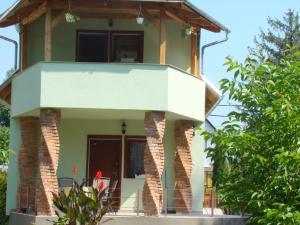 een groen huis met een balkon erop bij Krémer Vendégház in Harkány