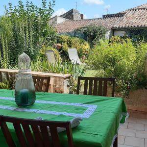 einen Tisch mit einem grünen Tischtuch und einer Vase darauf in der Unterkunft Gite de la Sauvetat in Auvillar