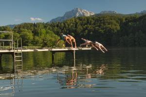 dos personas saltando al agua en un lago en Klosterwirt Höglwörth en Anger