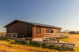 ein Blockhaus mit einem Tisch und Bänken auf einem Feld in der Unterkunft Riverfront Lodge Hella in Hella