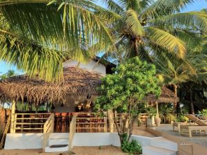a resort with a thatched roof and palm trees at Golden Beach Paradise in Tangalle