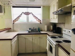 a kitchen with a sink and a stove and a window at Hastings Towers 3D Studio Apt Opp Beach in Bridgetown