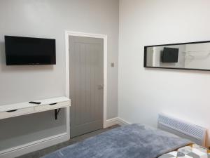 um quarto branco com uma cama e uma televisão na parede em Stunning 5 bed house, 2 mins to beach and town, with free parking em Blackpool