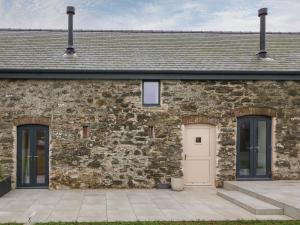 a stone house with a white door and two windows at Beudy in Gwalchmai