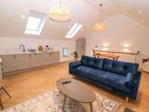 a living room with a blue couch and a table at Beudy in Gwalchmai