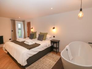 a bedroom with a bath tub and a bed and a bath tub at Beudy in Gwalchmai