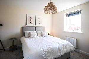 a bedroom with a bed with white sheets and a chandelier at Fairfields Gem by by PAY AS U STAY in Milton Keynes