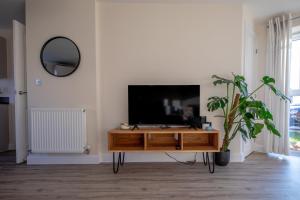a living room with a tv and a wooden entertainment center at Fairfields Gem by by PAY AS U STAY in Milton Keynes