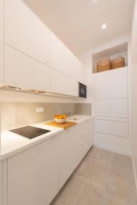 eine weiße Küche mit weißen Schränken und einer Schüssel Orangen in der Unterkunft Mayenne in Paris