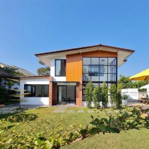 a large house with a grass yard in front of it at Benja369 บ้านเบญจา in Ban Fang Min