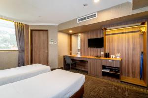a hotel room with two beds and a desk at YMCA One Orchard in Singapore