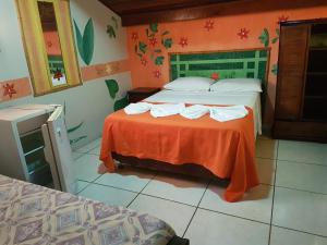 Peruíbe Suíte Flat Hotel في بيرويبي: غرفة في الفندق بسريرين وملاءات برتقالية
