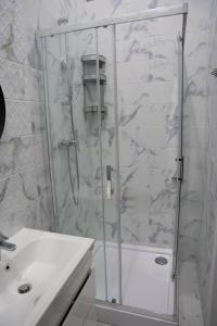 eine Dusche mit Glastür neben einem Waschbecken in der Unterkunft Soho Apartments Lviv in Lwiw