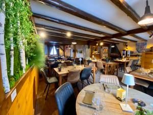 un restaurante con mesas, sillas y plantas en la pared en Hôtel Les Ancolies à Arêches, en Arêches