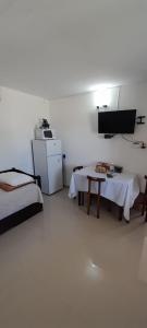a room with two beds and a table and a refrigerator at Apartamento Familiar Marta in Colonia del Sacramento