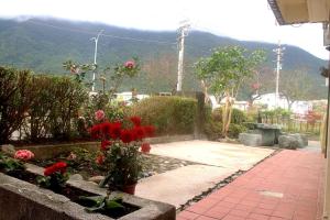 Ziyuan Homestay في Kangle: حديقة فيها ورد احمر واطلالة على جبل
