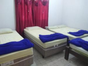 3 camas individuales en una habitación con cortinas rojas en Santo Ivo 3, en Aparecida