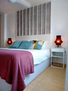 1 dormitorio con 1 cama blanca grande y 2 lámparas en Duplex with sea views, garden and terrace, en Santa Cruz de Tenerife