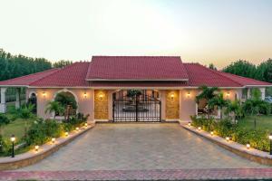 a house with a gate and a driveway at Desert Palms by StayVista in Kutch, nestled in orchards, features a swimming pool and a scenic balcony for a serene getaway in Shinaya