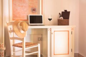 a desk with a computer and a glass of wine at Domo La Vela - Affittacamere - Living Sant'Antioco in SantʼAntìoco