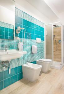 Baño de azulejos azules con aseo y lavamanos en Domo LA VELA, en SantʼAntìoco
