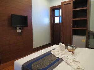Habitación de hotel con 1 cama con toallas y TV. en Baanlek Home Stay en Chiang Mai