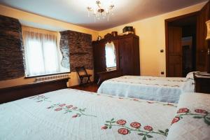 a bedroom with two beds and a chandelier at Apartamentos Rurales Los Galpones in Coaña
