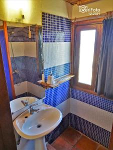 baño de azulejos azules con lavabo y ventana en La Posada, en Punta del Diablo