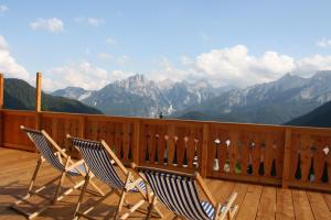 three chairs on a deck with a view of mountains at HG Hotel La Caminatha in Val di Zoldo +101 photos