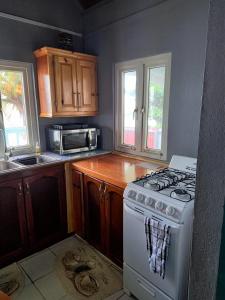 uma cozinha com um fogão branco e um micro-ondas em Mx2 Cottage em Calibishie