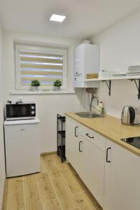 a kitchen with white cabinets and a sink and a window at River Park apartments Ukmerge in Ukmergė