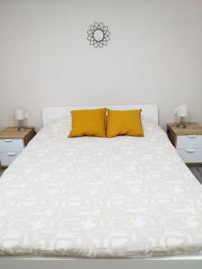 a white bed with two yellow pillows on it at Ca la Lola in L'Escala