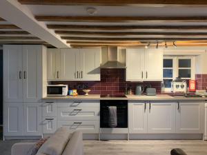 a kitchen with white cabinets and a couch in a room at Apartment Two, The Carriage House, Bilbrough, York in York