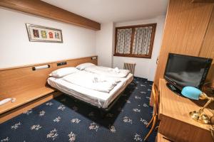 a small bedroom with a bed and a flat screen tv at Hotel Renzi in Folgarida