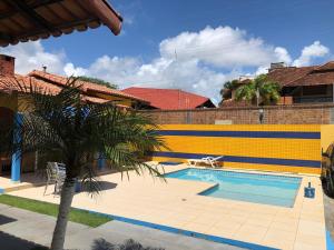 a swimming pool with a palm tree in front of a building at Salinopolis- casa com piscina in Salinópolis