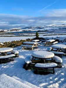 un grupo de mesas de picnic cubiertas de nieve en The Boshaw Trout en Holmfirth