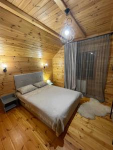 ein Schlafzimmer mit einem Bett in einem Holzzimmer in der Unterkunft Girske Povitria Cottage in Jaremtsche