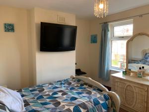 a bedroom with a flat screen tv on the wall at Busy Bee - Guest House - Self Service in Leigh