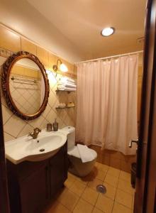 a bathroom with a sink and a toilet and a mirror at Valentini Guesthouse in Karpenisi