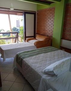 two beds in a room with a balcony at Pousada Palmeiras in Bombinhas